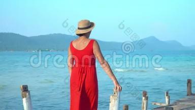 穿着红色长裙的女人.. 这位穿红色衣服的年轻女子在码头上<strong>花钱</strong>，远远地看着。 蓝色海洋